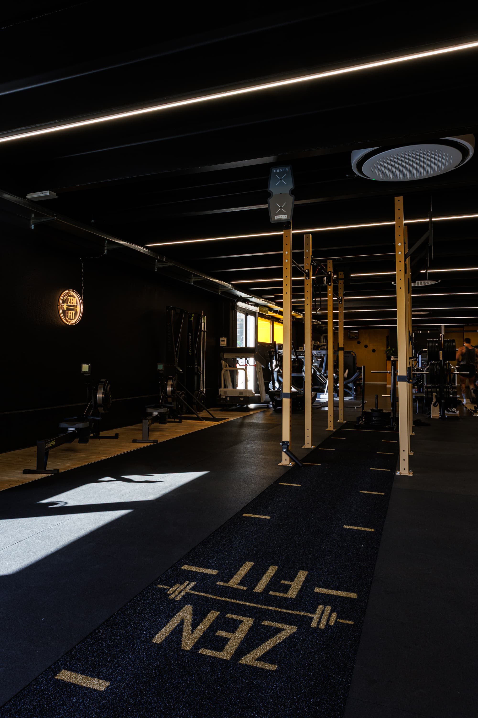 La corsia dell'area functional con la scritta ZENFIT sul pavimento e i rack in legno di fianco.